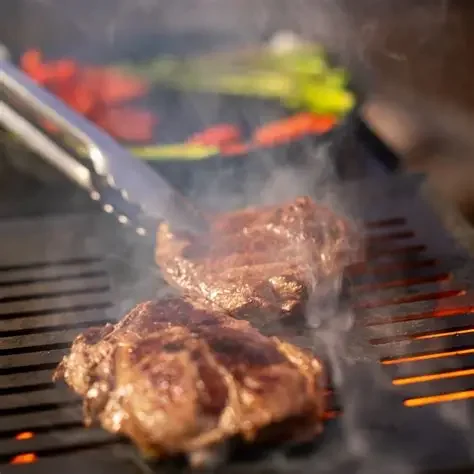 Steaks grilling over open flame — food served from a PadSite kitchen