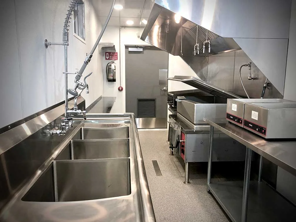 PadSite ready-built commercial kitchen interior — stainless steel sinks, 10-foot exhaust hood, and cooking line